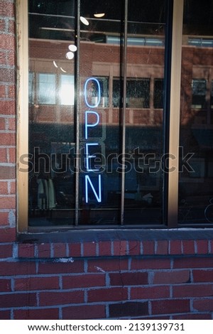 Blue neon open sign in window of brick building