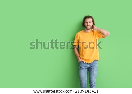 Handsome young man in stylish t-shirt on green background