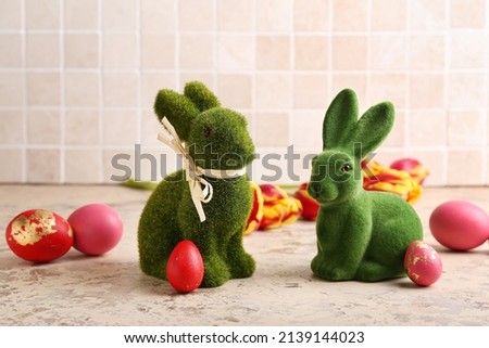 Cute Easter bunnies and painted eggs on light background