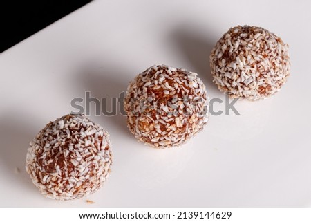 Beautiful sweets with coconut on a white plate on a black background close-up