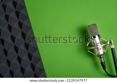 Microphone on green background with copy space and acoustic foam panel