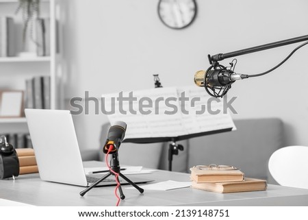 Modern workplace with laptop, books and microphones in room
