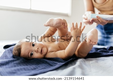 Mother changing baby's diaper in bed. Mother applies diaper rash cream. Royalty-Free Stock Photo #2139154641