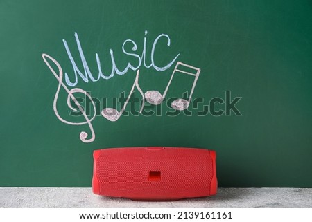 Wireless portable speaker, drawing of music notes and word MUSIC on green background