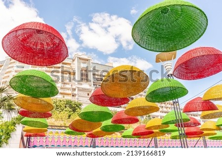 There are umbrellas hanging over the park alley. Against the background of the blue sky, umbrellas with colorful autumn colors. Colorful picture.