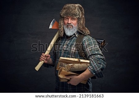 Old man woodman holding hatchet and stack of lumber Royalty-Free Stock Photo #2139181663