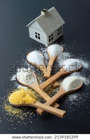 Wooden teaspoons with flour, salt, sugar,  semolina, and corn flour, leading to a miniature white house
