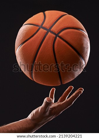 Time to raise your game. Cropped image of a mans hand holding a basketball against a black background.