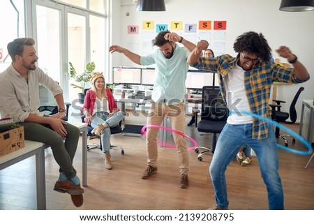 A group of employees is having fun while playing with hula-hoop in a relaxed atmosphere in the office. Employees, job, office Royalty-Free Stock Photo #2139208795