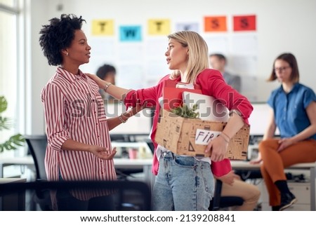 A young employee in a sad atmosphere in the office says goodbye to a colleague after she was fired. Employees, job, office Royalty-Free Stock Photo #2139208841