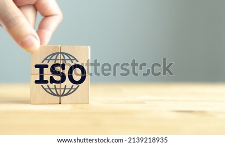 ISO standards quality control certification concept. Quality warranty and assurance.  Hand puts wooden cubes with ISO and smart globe icons on grey background and copy space. Modern ISO banner. Royalty-Free Stock Photo #2139218935