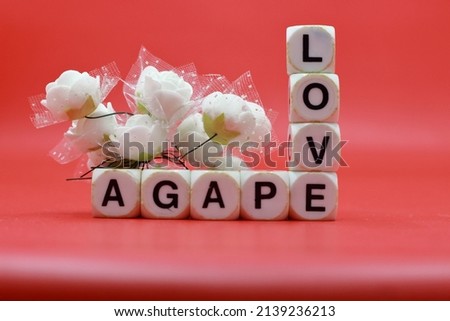 Pile of dice with letters forming the word LOVE AGAPE on a red background
