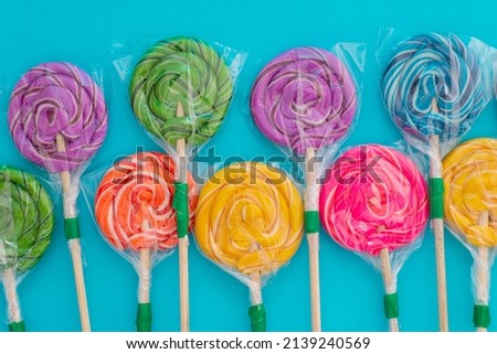 Candy in the form of colorful lollipops on a blue background. Background made with colorful candies.