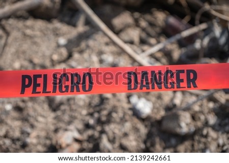 Red tape at accident or crime scene reading danger (English) and Peligro (Spanish).