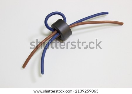 Ferrite ring for protection against electromagnetic interference in the wire. High-frequency protection of electronic equipment against inductive interference. Electromagnetic protection. Royalty-Free Stock Photo #2139259063
