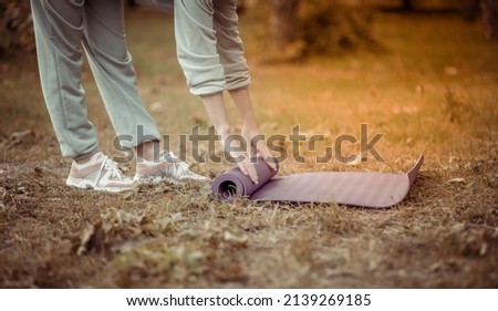 Sport woman unwinds yoga mat on the grass