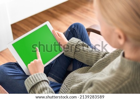 Digital tablet with empty black screen. Young girl holding tablet pc in her hands with blank green screen. Concept for video-sharing platform
