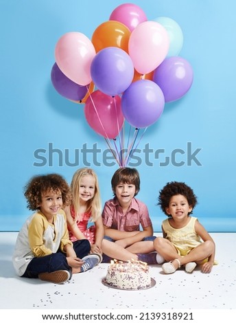 My birthday wish is to be friends forever. Shot of a group of children sitting around a birthday cake with bunch of balloons in the background.