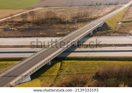 A vast plain. A collision-free intersection of two roads. One of them is two-lane, the other runs along the flyover. View from the drone. Royalty-Free Stock Photo #2139333593