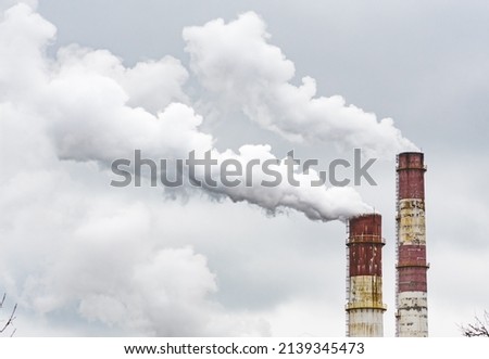 Thick white smoke from industrial factory old rusty chimneys on a cloudy grey sky background Royalty-Free Stock Photo #2139345473