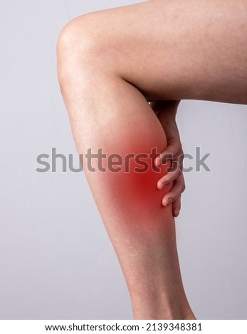 Woman suffering from calf muscle pain. Hand holding leg with red spot closeup. Muscle strain, spine, veins diseases. Health problems concept. High quality photo
