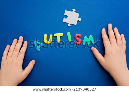 Autistic kid hands holding puzzle jigsaw and word autism, mental health concept. Autism spectrum, disorder. World autism awareness day.