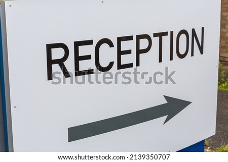 Reception sign with black text on white and a light grey directional arrow
