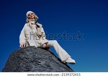 woman in autumn clothes stands on a rock landscape blue sky lifestyle