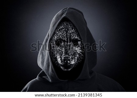 Wolf in hooded cloak at night over dark misty background Royalty-Free Stock Photo #2139381345