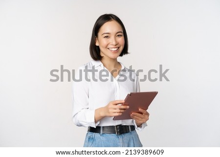 Image of young ceo manager, korean working woman holding tablet and smiling, standing over white background