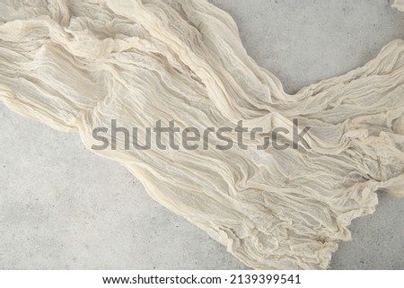 Wrinkled gauze fabric on light grunge stone background. Cotton gauze fabric cloth on stone tile surface with copy space. Royalty-Free Stock Photo #2139399541