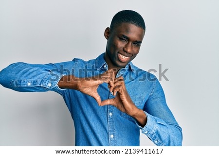 Young african american man wearing casual clothes smiling in love doing heart symbol shape with hands. romantic concept. 
