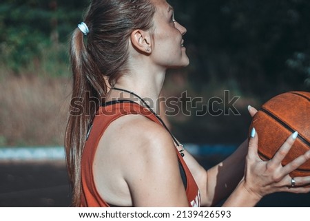 A girl in a red T-shirt is playing basketball