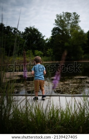 Boy standing at pond in summer