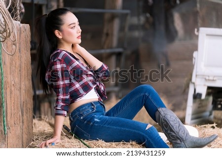 Young adult Asian woman fashion in natural environment. Beautiful cowgirl in the stable. Cheerful cute model in western style. Cowboy girl.