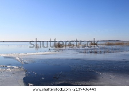 Earlier spring scenery with lake covered with a bit of ice and clear blue sky. High quality photo