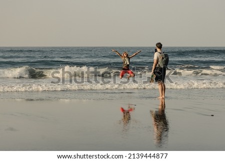 Family trip, mother taking pictures of her daughter on the shore with her smartphone