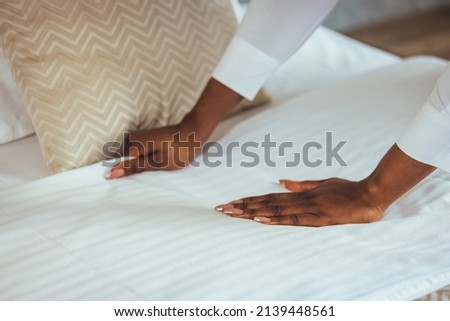 African maid making bed in hotel room. Staff Maid Making Bed. African housekeeper making bed. Maid working at a hotel making the bed. Housekeeper cleaning a hotel room Royalty-Free Stock Photo #2139448561
