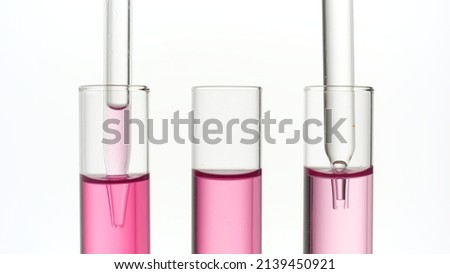 Three test tubes with pink liquid and lab droppers on white background | Abstract body care cosmetics formulation concept Royalty-Free Stock Photo #2139450921