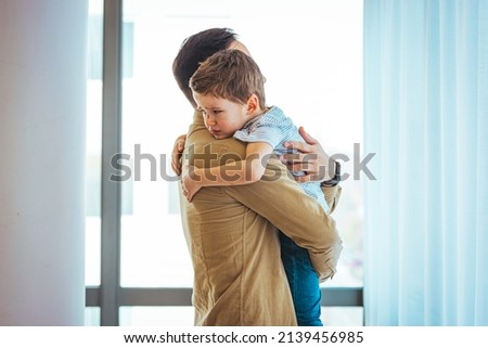 Closeup Sad young blond boy crying on father hands indoor. Man holds son, hugs and comforts. Family love, care and moral support, baby's tears, daddy's arms. Dad consoling crying child
