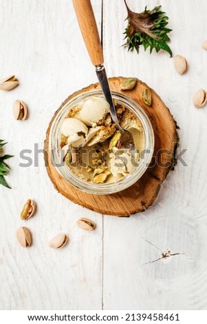 Homemade pistachio ice cream in a glass jar fresh pistachio over white background. vertical image. top view. place for text,