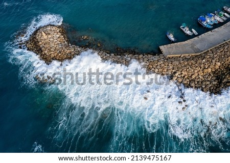 Aerial drone view of fishing boats moored at the harbor at breakwater. Stormy waves at sea Peyia, Cyprus Royalty-Free Stock Photo #2139475167