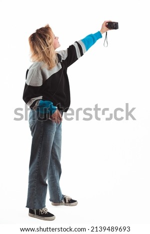90s vibes. Girl taking selfie with vintage digital camera. Vertical studio shot. Copy space. White background. High quality photo
