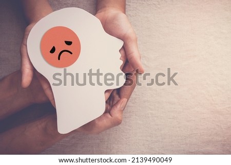 Adult and child hands holding sad face in brain paper cutout, unhappy hormones, imbalance brain chemicals, negative mental health concept Royalty-Free Stock Photo #2139490049