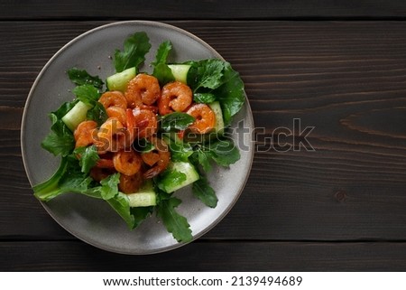 Fresh salad with grilled shrimps, cucumbers and arugula beautifully served on a plate, top view, flat lay