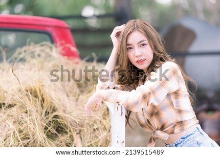 Beautiful cowgirl style model posing on farmland. Young adult Asian woman fashion in natural environment. Beautiful cowgirl in the stable. Cowboy girl.