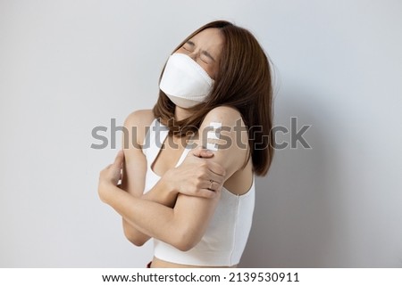 Concept image of fully vaccinated asian woman getting boosted with the first booster, experiencing headache, fever, adverse event side effect after vaccine booster shot Royalty-Free Stock Photo #2139530911