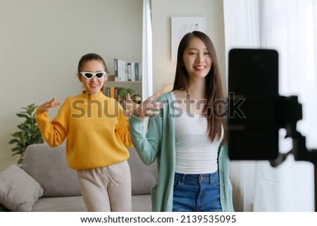 Asian young woman with her friend tiktoker created her dancing video by smartphone camera together. To share video to social media application Royalty-Free Stock Photo #2139535095