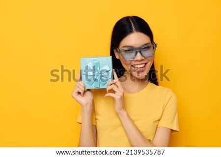 Charming young Asian woman in stylish glasses a gift fun studio model unaltered