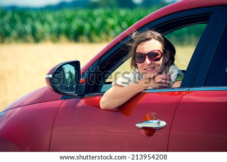 Beautiful girl with fashion sunglasses, looking out of the car